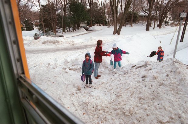 Suzanne Weaver, 2nd from left, with daughters Sarah Martinez, 8, left; Jessica Martinez, 5, center; and David Woodley, 6, right, climb over a snow bank to get on the school bus to Clearview Elementary School in Bethlehem after a week off due to blizzard of 1996. (Young Hong/The Morning Call)