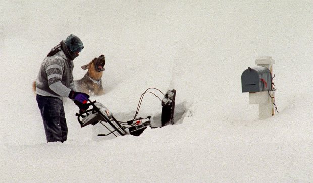 Mike Pratt of Sheaf Lane in Center Valley works trying to clear his driveway and mailbox from three feet of snow as his dog Moose tries to catch the snow as it is blown through the air after the blizzard of 1996, Jan. 8, 1996. (John C. Anderson/The Morning Call)