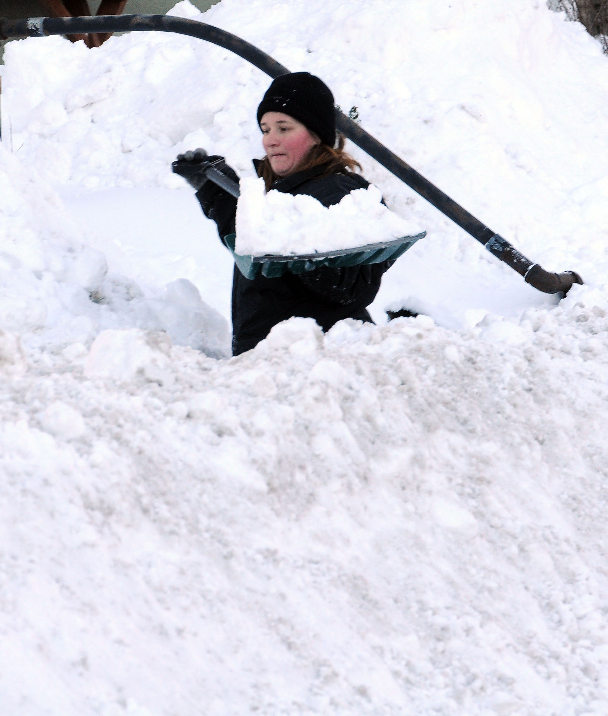 Melissa Cain lifts a shovel full of snow on Sunday,...