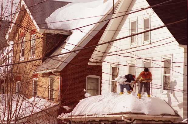 Dave Rush (facing camera) and Terry Bast shovel snow from the roof of a home on Juniper Street in Quakertown, just a few doors down from where a porch collapsed in front of several row homes following the blizzard of 1996, Jan. 13, 1996. (Doug Benedict/The Morning Call)