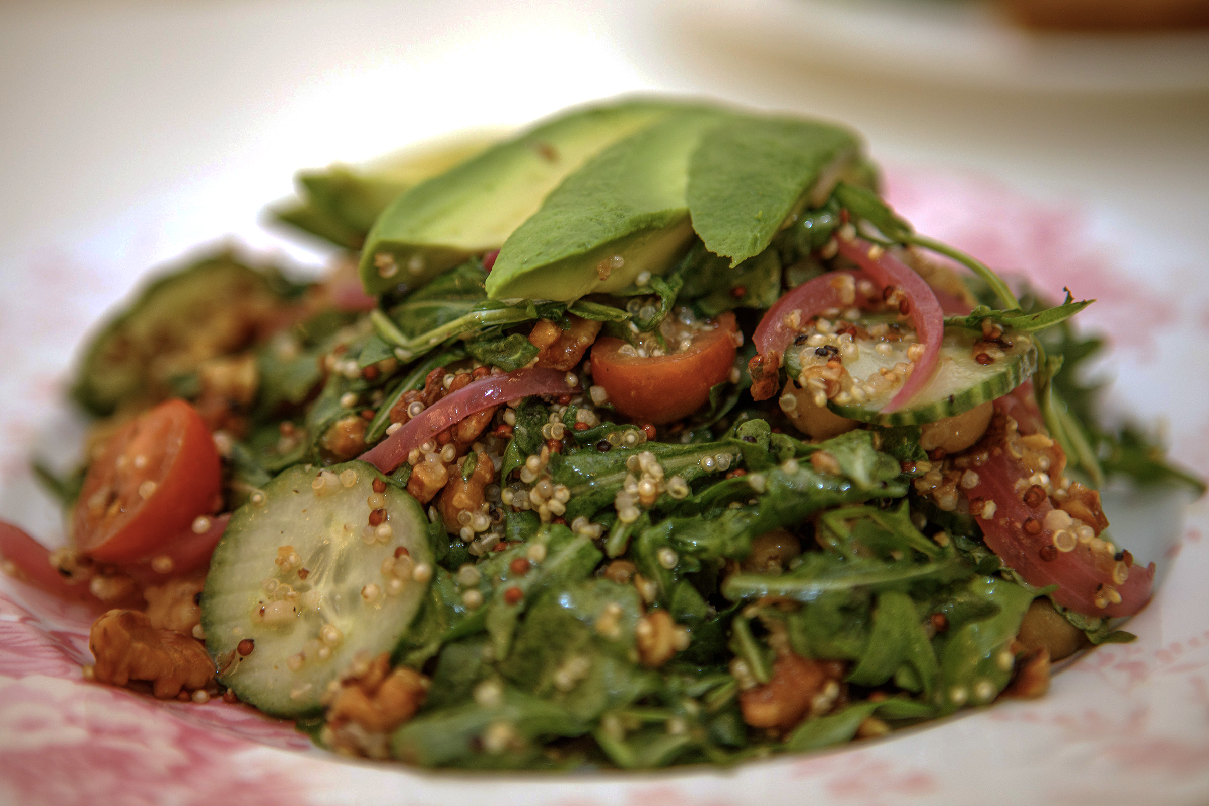 An avocado, tomato and cucumber arugula salad topped with quinoa...