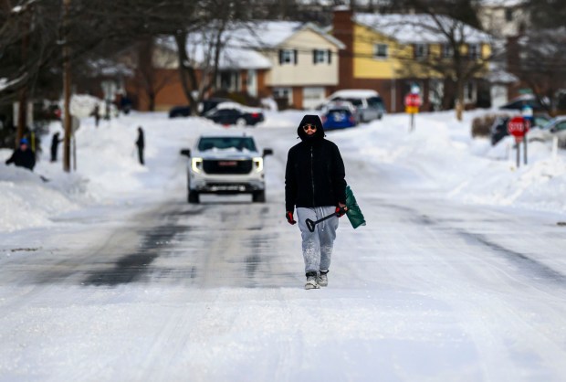A pedestrian with a shovel walks along a snowy road Monday, Jan. 26, 2026, in Bethlehem after Sunday's storm that dropped more than a foot of snow in some parts of the Lehigh Valley. (April Gamiz/The Morning Call)