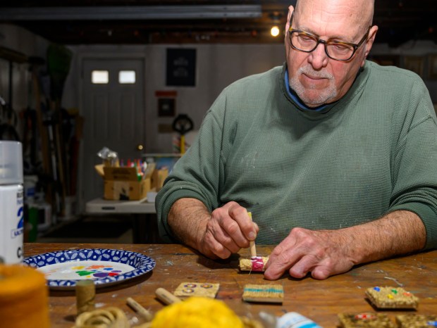 Dave Jacoby of Bethlehem Township paints experimental art on tiles Tuesday, Jan. 6, 2026, in Bethlehem Township. As part of an idea he had years ago that he calls WOA! (World of art!), Jacoby leaves the tiles in various place to cheer up people at a time when there is fear, anger and sadness in the world. He started a Facebook page and gives the tiles to people, asking them to spread the art and upload a photo and a post about where it was placed. (April Gamiz / The Morning Call)