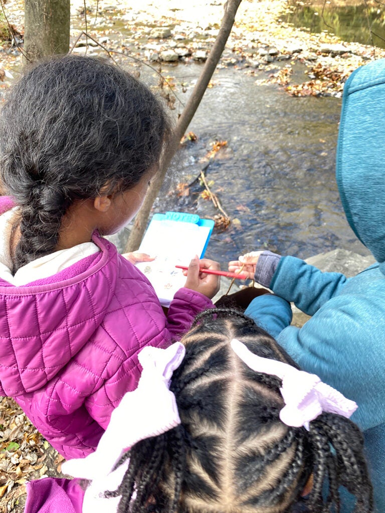 Children look at a notebook outside
