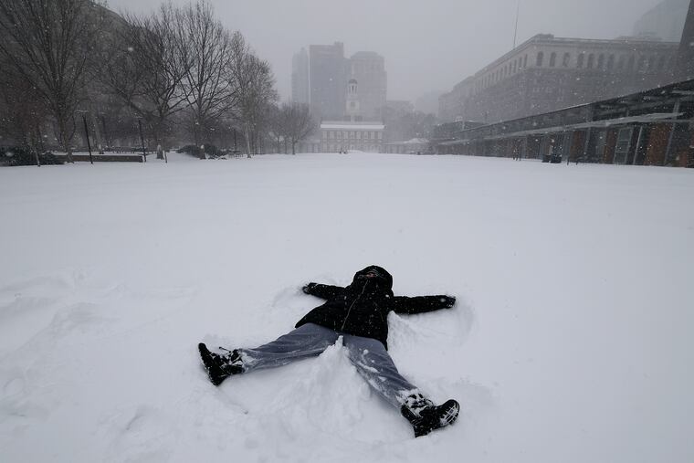 Julie Cohen makes a snow angel on the snow-covered lawn at the Independence Mall on Sunday.