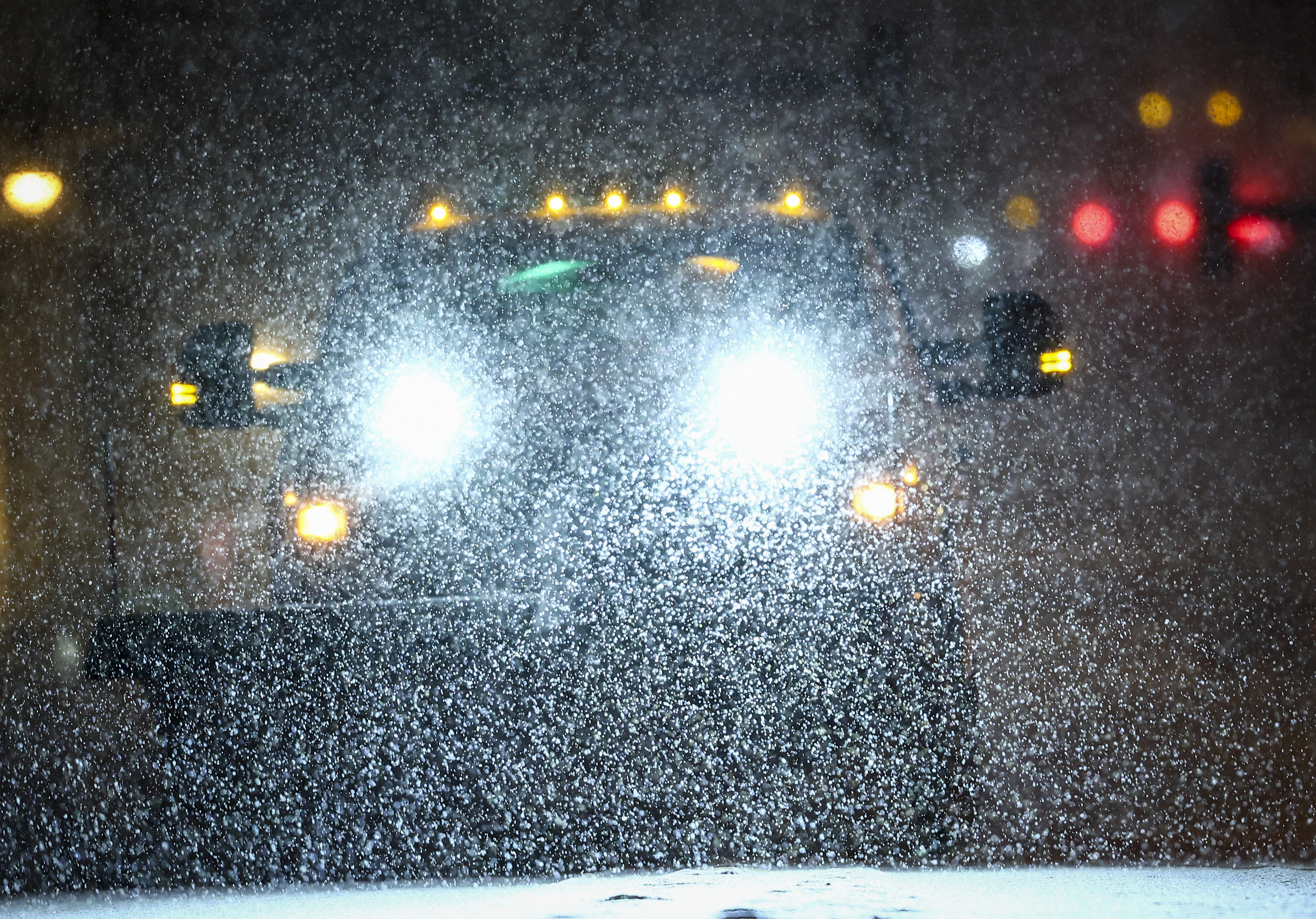 Snow flakes are illuminated by the headlines of a plow truck in Easton around 7:00 a.m. Sunday, Jan. 25, 2026.