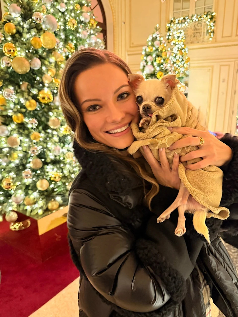 Caitlin O'Connor holding Bubbles next to a Christmas tree.