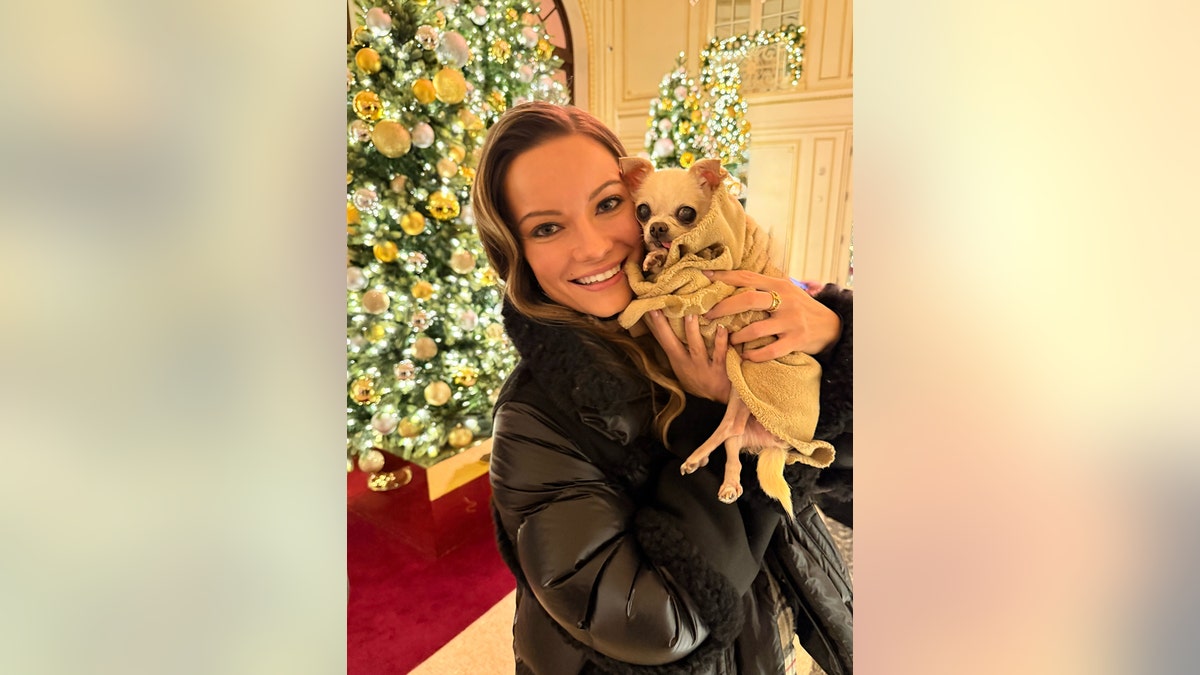 Caitlin O'Connor holding Bubbles next to a Christmas tree.