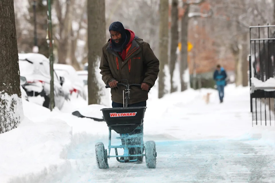 A person spreads salt on a sidewalk on Jan. 26 in the Flatbush neighborhood of the Brooklyn borough in New York City. 
