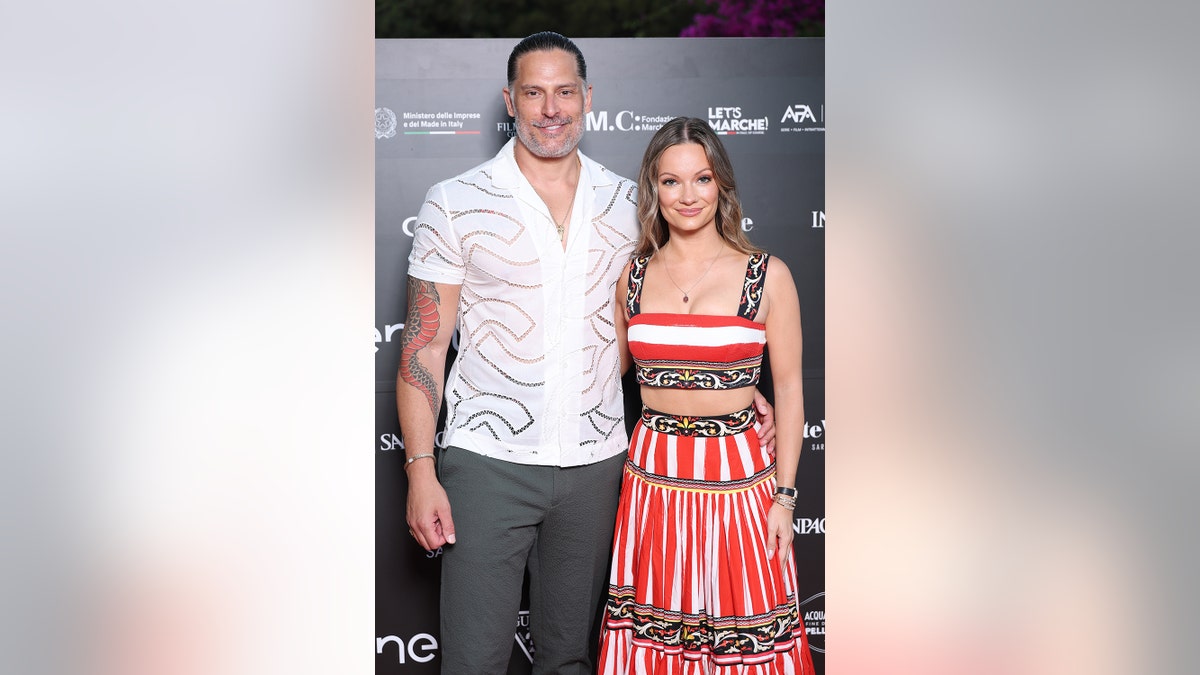 Joe Manganiello and Caitlin O'Connor wearing festive attire as they lovingly pose together on the red carpet.