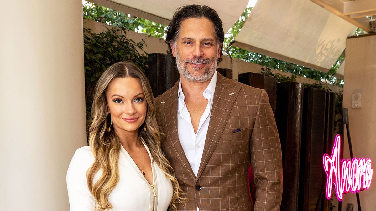 Caitlin O'Connor wearing a white dress and Joe Manganiello wearing a brown blazer with a matching white shirt.