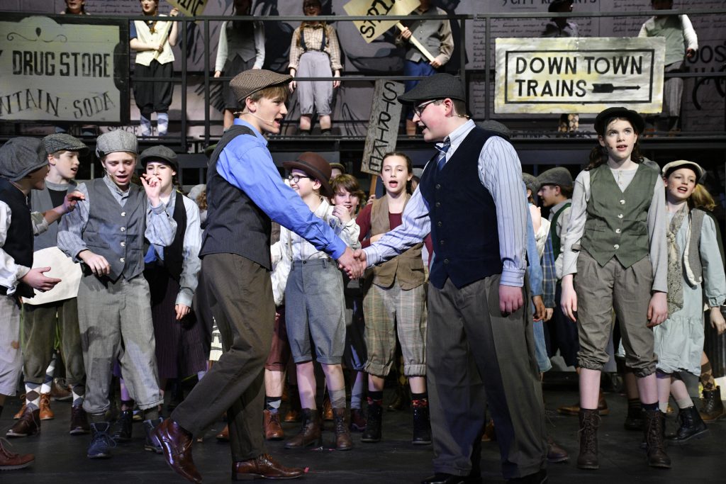 students performing in costume on stage