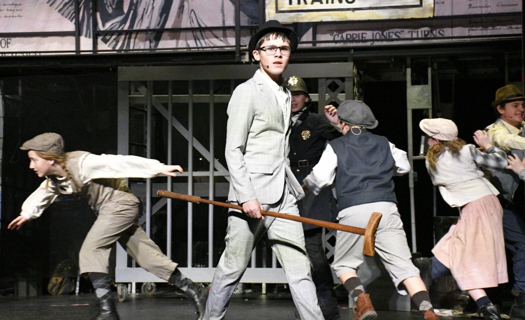 students performing in costume on stage