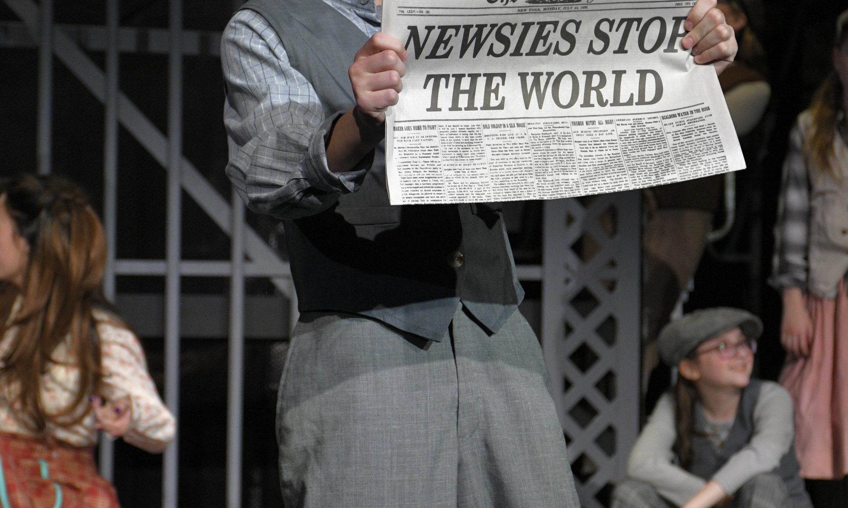student singing on stage holding newspaper