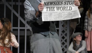 student singing on stage holding newspaper