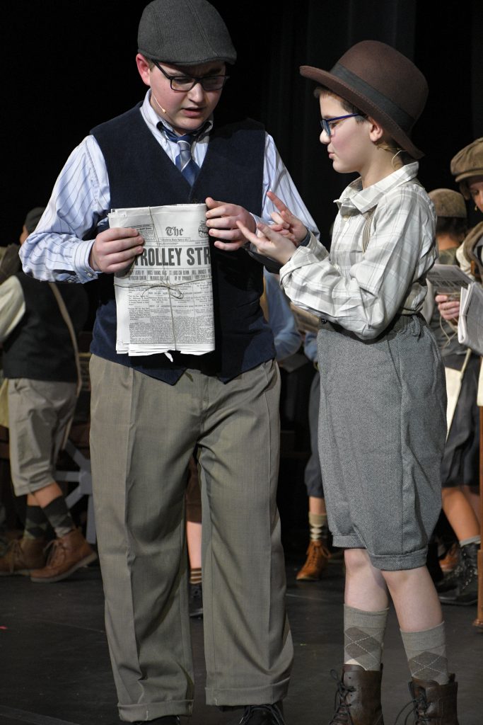 students performing in costume on stage