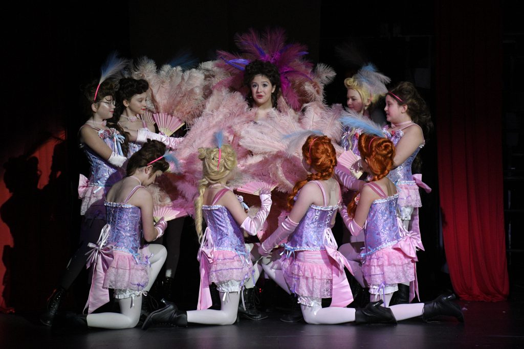students performing in costume on stage