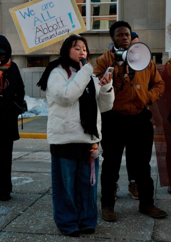 Ella Nguyen speaking into a megaphone at the rally in front of the School Board building