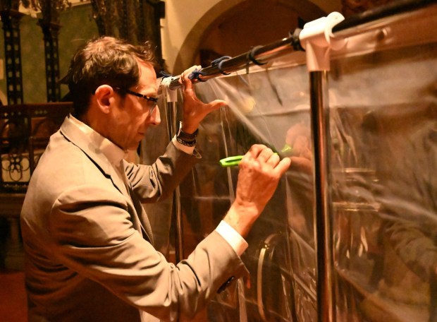 Allentown Mayor Matt Tuerk participates in a pain into power activity after a vigil for Renee Nicole Good, the woman shot and killed by a federal immigration agent in Minneapolis, on Friday, Jan. 9, 2026, at the Cathedral Church of the Nativity in Bethlehem. For the activity people were asked to look into a shower curtain and write what they saw on the other side. (Amy Shortell/The Morning Call)