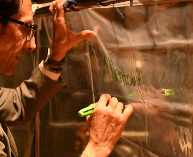 Allentown Mayor Matt Tuerk participates in a pain into power activity after a vigil for Renee Nicole Good, the woman shot and killed by a federal immigration agent in Minneapolis, on Friday, Jan. 9, 2026, at the Cathedral Church of the Nativity in Bethlehem. For the activity people were asked to look into a shower curtain and write what they saw on the other side. (Amy Shortell/The Morning Call)