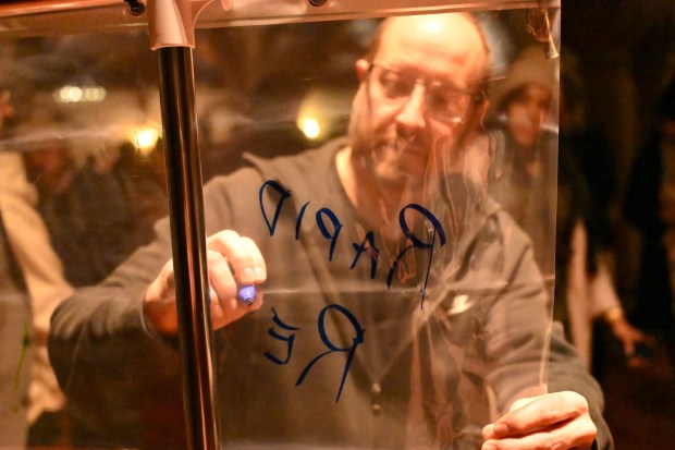 People participate in a pain into power activity after a vigil for Renee Nicole Good, the woman shot and killed by a federal immigration agent in Minneapolis, on Friday, Jan. 9, 2026, at the Cathedral Church of the Nativity in Bethlehem. The activity involved writing what you saw after looking into a shower curtain. (Amy Shortell/The Morning Call)