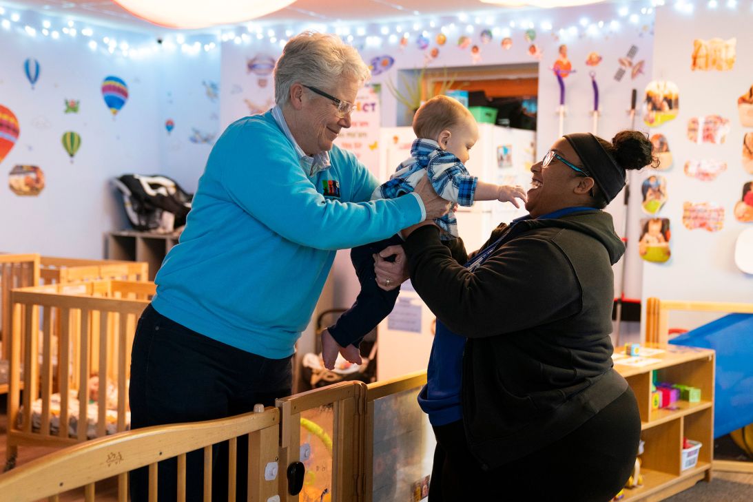 Dana Eldridge, left, hands her grandchild to an Active Learning Centers Emmaus staff member.
