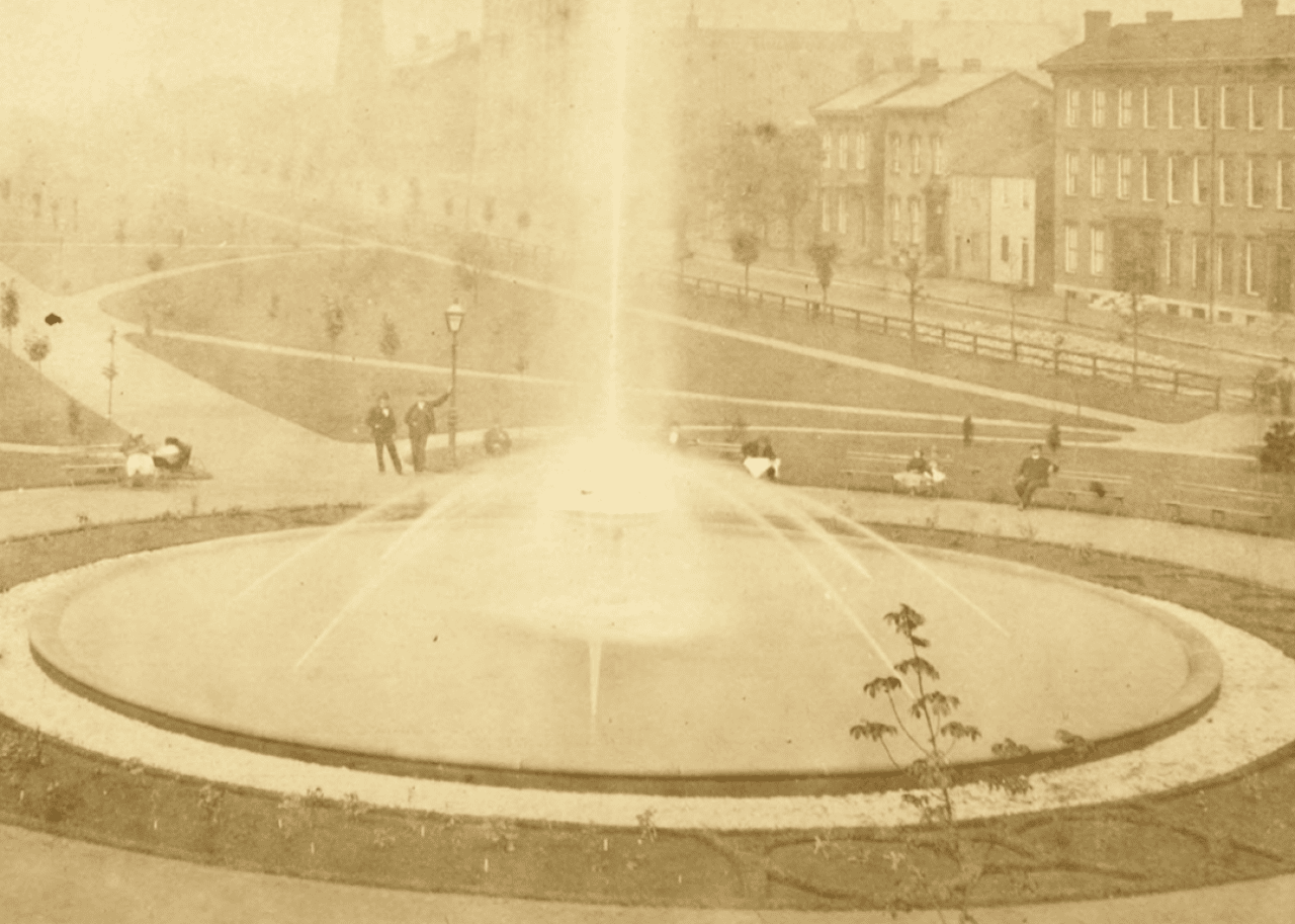 People sitting on benches by large fountain