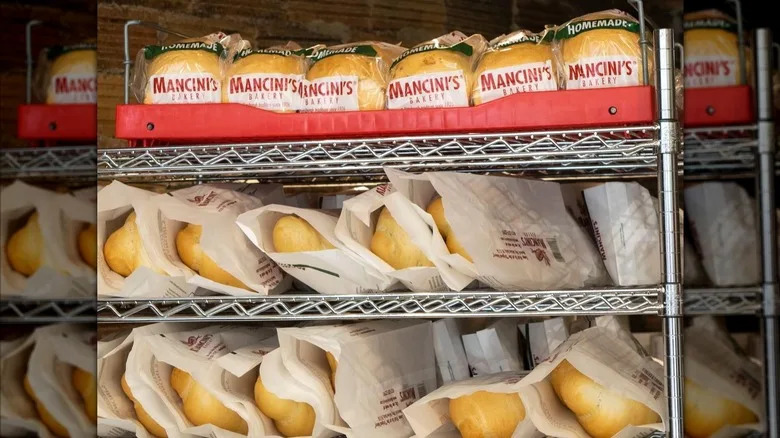 Loaves of Mancini's bread in paper bags on a shelf