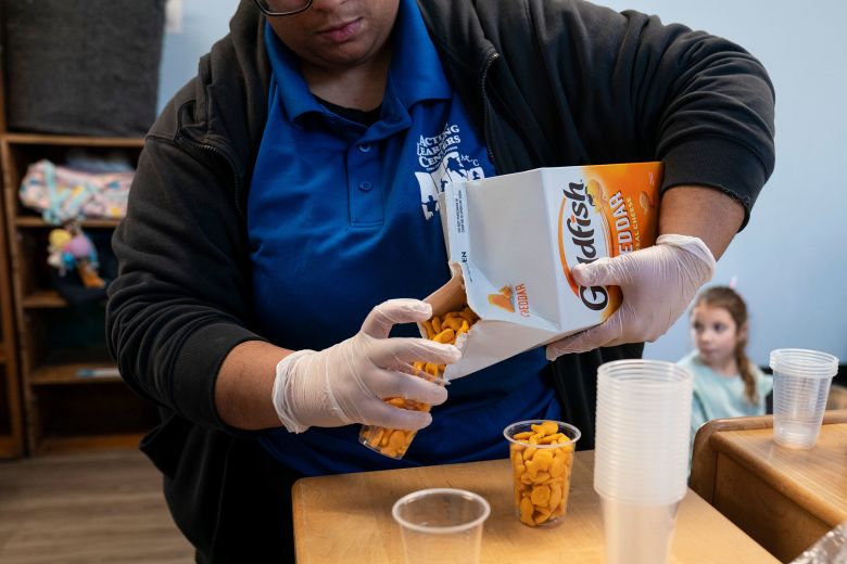 A staff member distributes crackers during snack time at Active Learning Centers Emmaus.