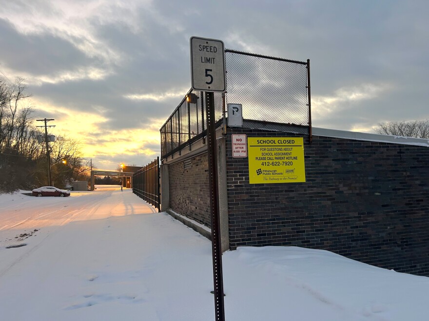 A yellow sign on a brick building next to a sidewalk of snow.