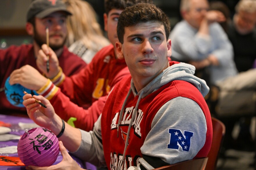 Roman Cutrufello, a junior at the University of Scranton, writes using a calligraphy brush on a lantern.