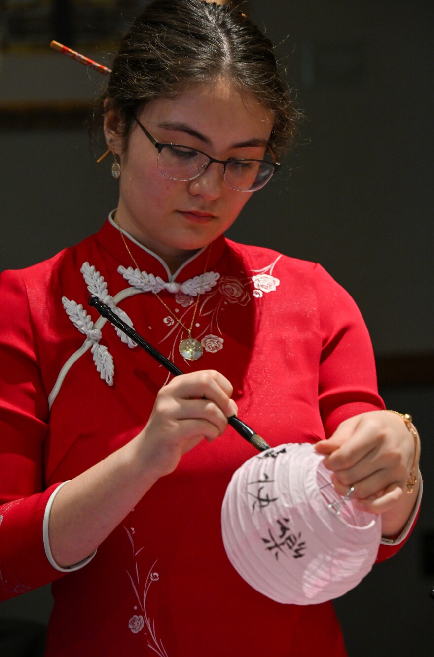 Mei Darnell, a freshman at the University of Scranton, writes calligraphy on a lantern.