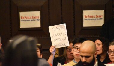 An opponent of the planned closure of Harding Middle School holds up a sign during City Council