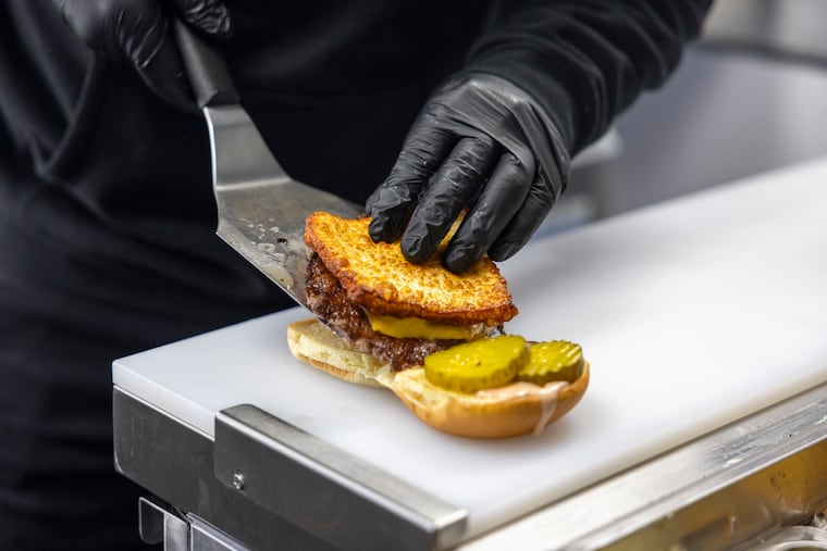 El Sazón R.D. co-owner Ari Valerio assembles the restaurant's viral Dominican smashburger at the restaurant's first Philly location, located at 1030 N 2nd St.