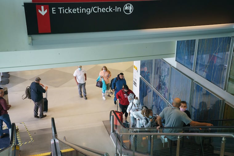 Passengers ride an escalator to Terminal E in the Philadelphia International Airport in this 2021 file photo.