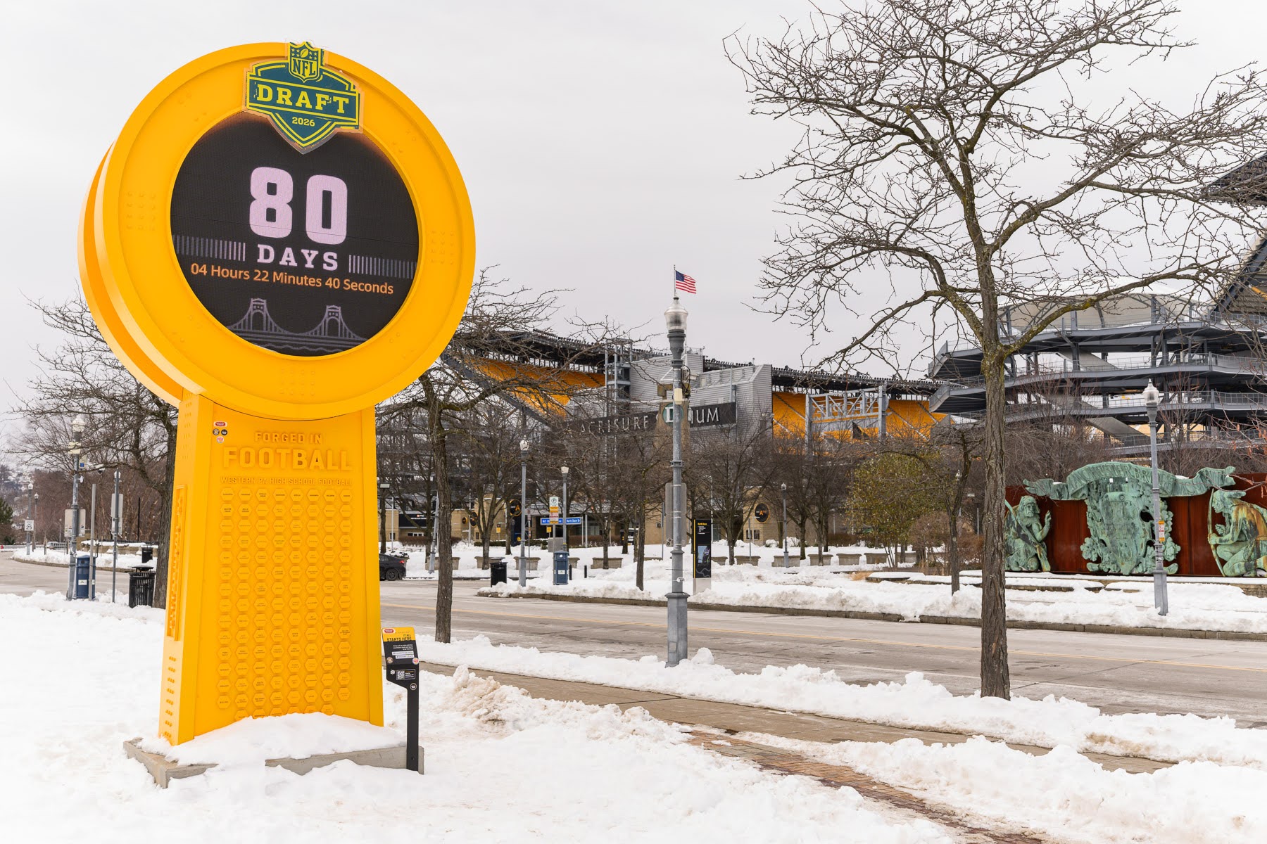 A large yellow NFL Draft countdown clock displays "80 days" on a snowy street with trees and a stadium in the background.
