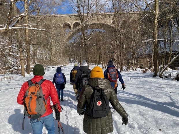 Walkers trudge through the snow along Forbidden Drive with the Henry Ave. Bridge lurking in the background. (Photo by JJ Tiziou)