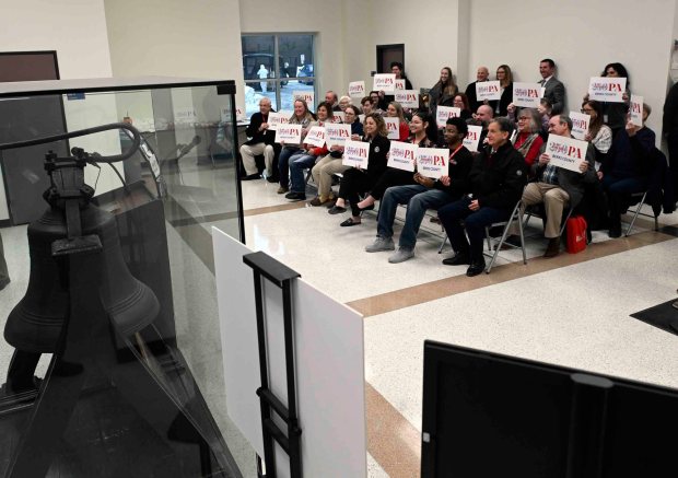 Guests display signs with Berks County's Liberty Bell  for America 250PA following an America 250PA Kickoff event on Friday at the Berks County Services Center.  (BILL UHRICH/READING EAGLE)