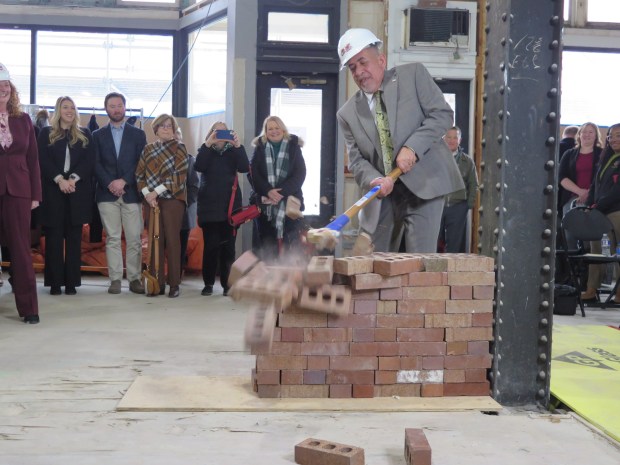 Reading Mayor Eddie Moran sends bricks flying with a swing of a sledge hammer during a "wall breaking" ceremony for renovations of the historic American House. (DAVID MEKEEL - READING EAGLE)