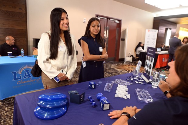 Vanesa Aguay Guerra, 19, of Wyomissing and her sister Karla Aguay 16, speak with representatives of Brentwood Industries during a banquet for the class of 2025 Emerging Entrepreneurs Academy on Friday, Aug. 1, 2025, at the DoubleTree by Hilton Hotel, 701 Penn St. (BILL UHRICH/MEDIANEWS GROUP)