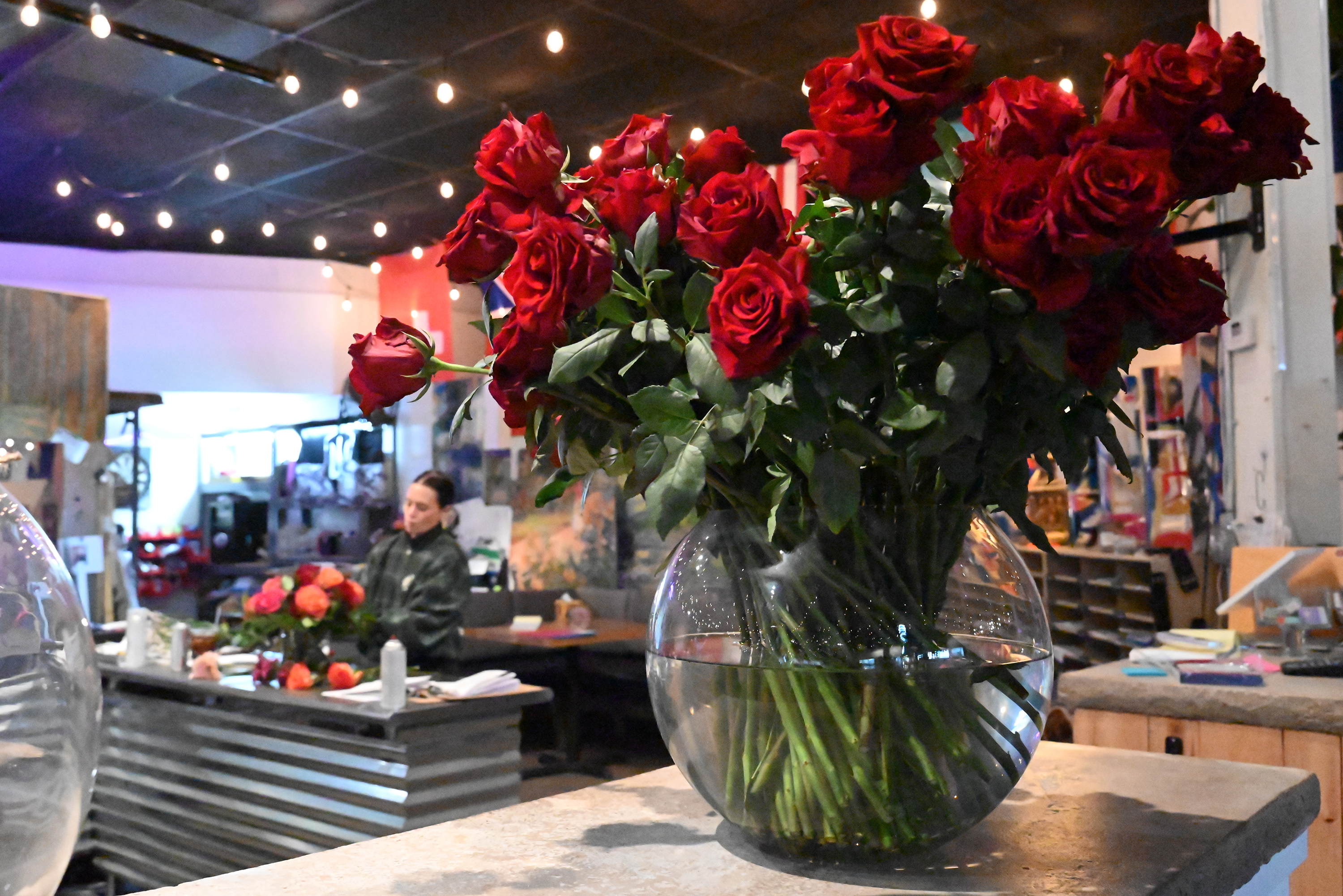 A vase full of roses sits on a counter at...