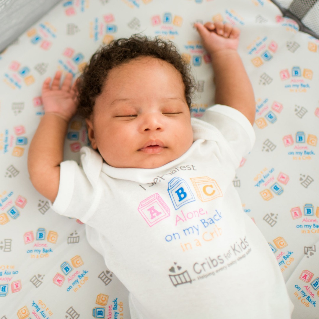 The photo depicts a baby sleeping safely on their back,...