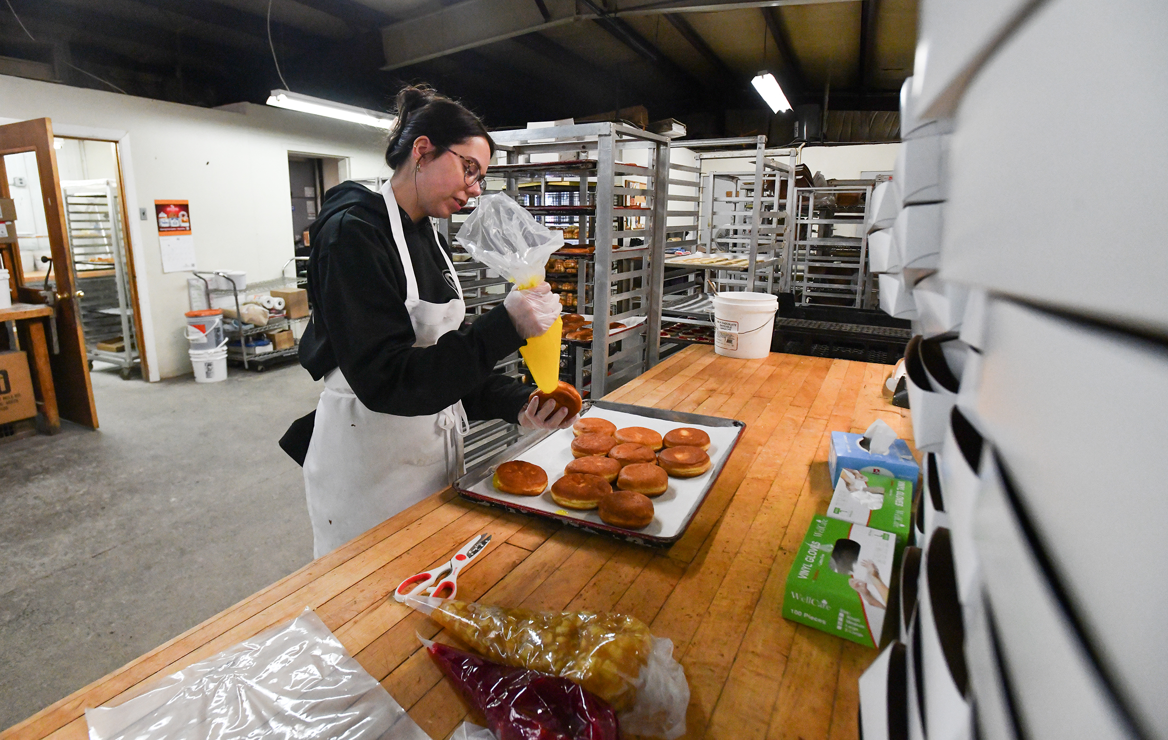 Manager Candace Fox fills pÄczki doughnuts with lemon filling Monday,...