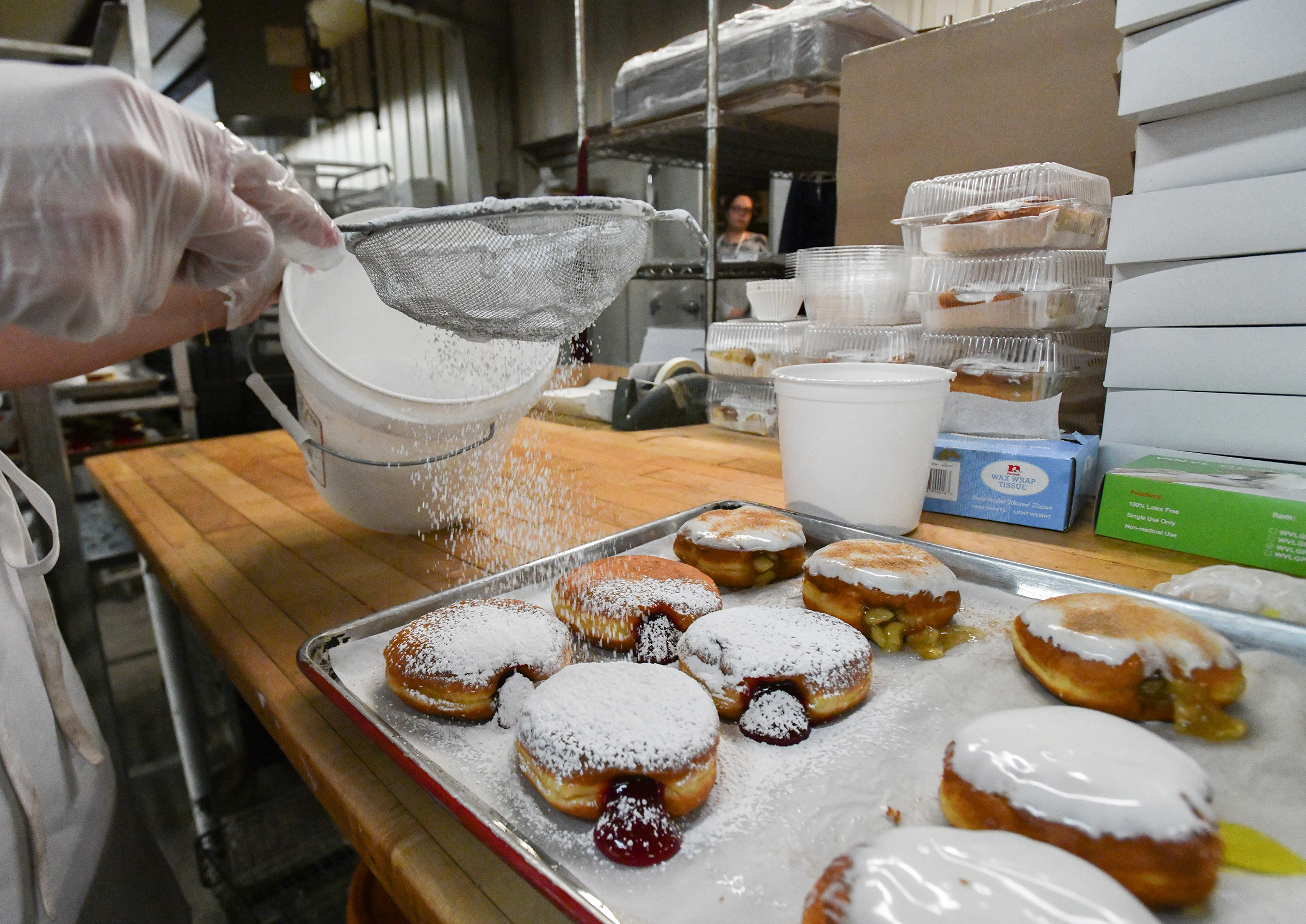 Manager Candace Fox tops raspberry-filled pÄczki doughnuts with powdered sugar...