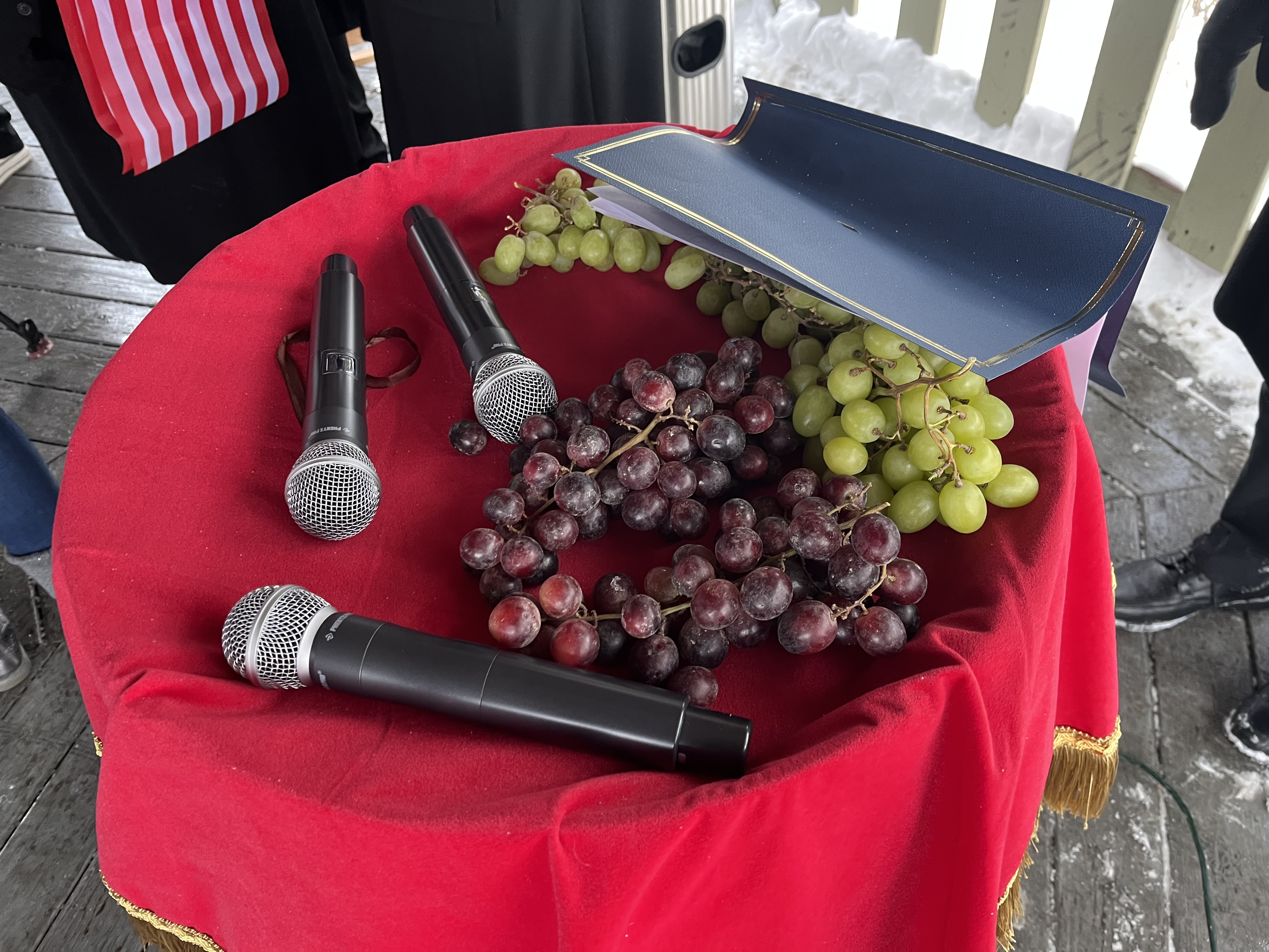 Red and white grapes, sitting atop a wine barrel, were...