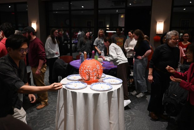 Attendees participate in a chop stick challenge during the Asian New Year Festival and Workshop at the University of Scranton on Thursday, Feb. 19, 2026. Tables worked together to move popcorn and M&M's to the plates on the center table. (REBECCA PARTICKA/STAFF PHOTOGRAPHER)