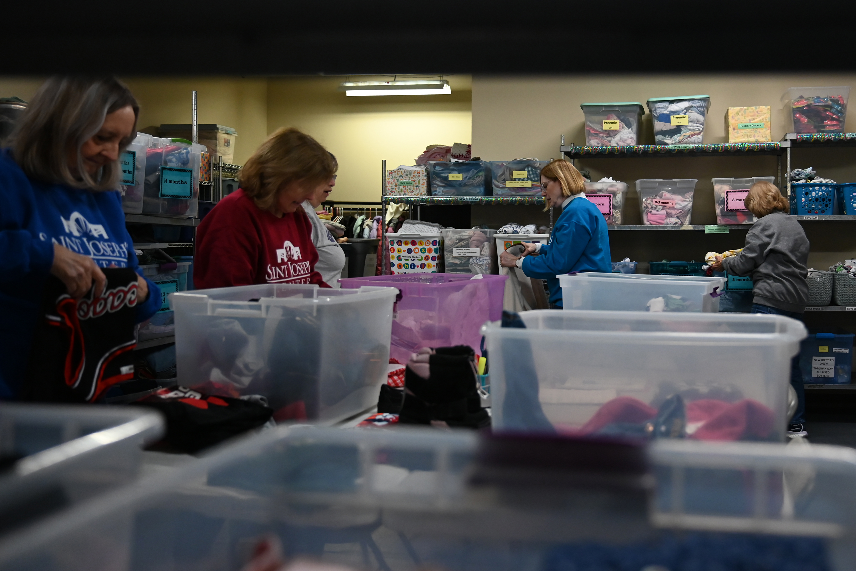 Volunteers organize donations for the children's clothing drive at the...