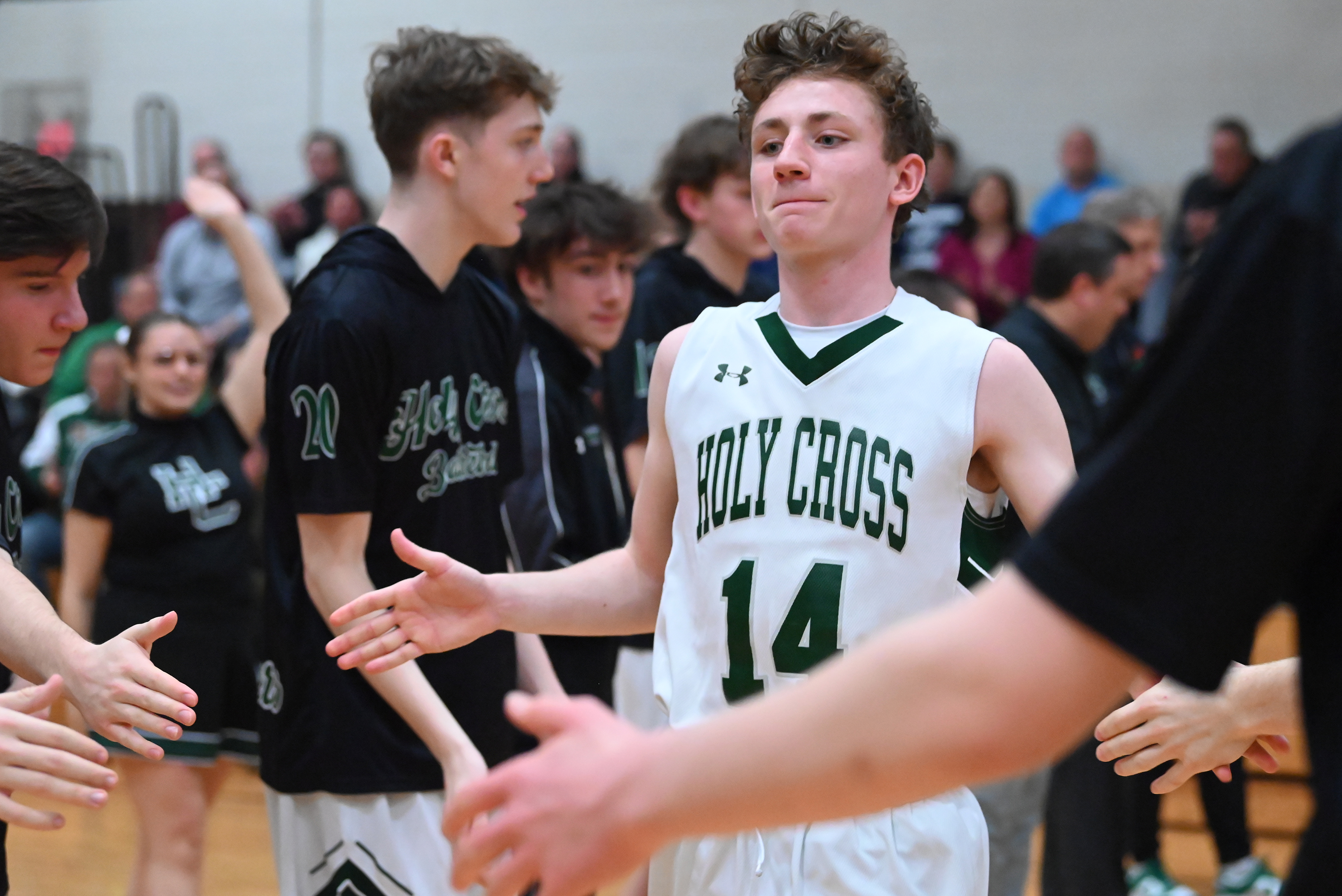 Holy Cross’ Colin Farrell high fives his teammates before the...