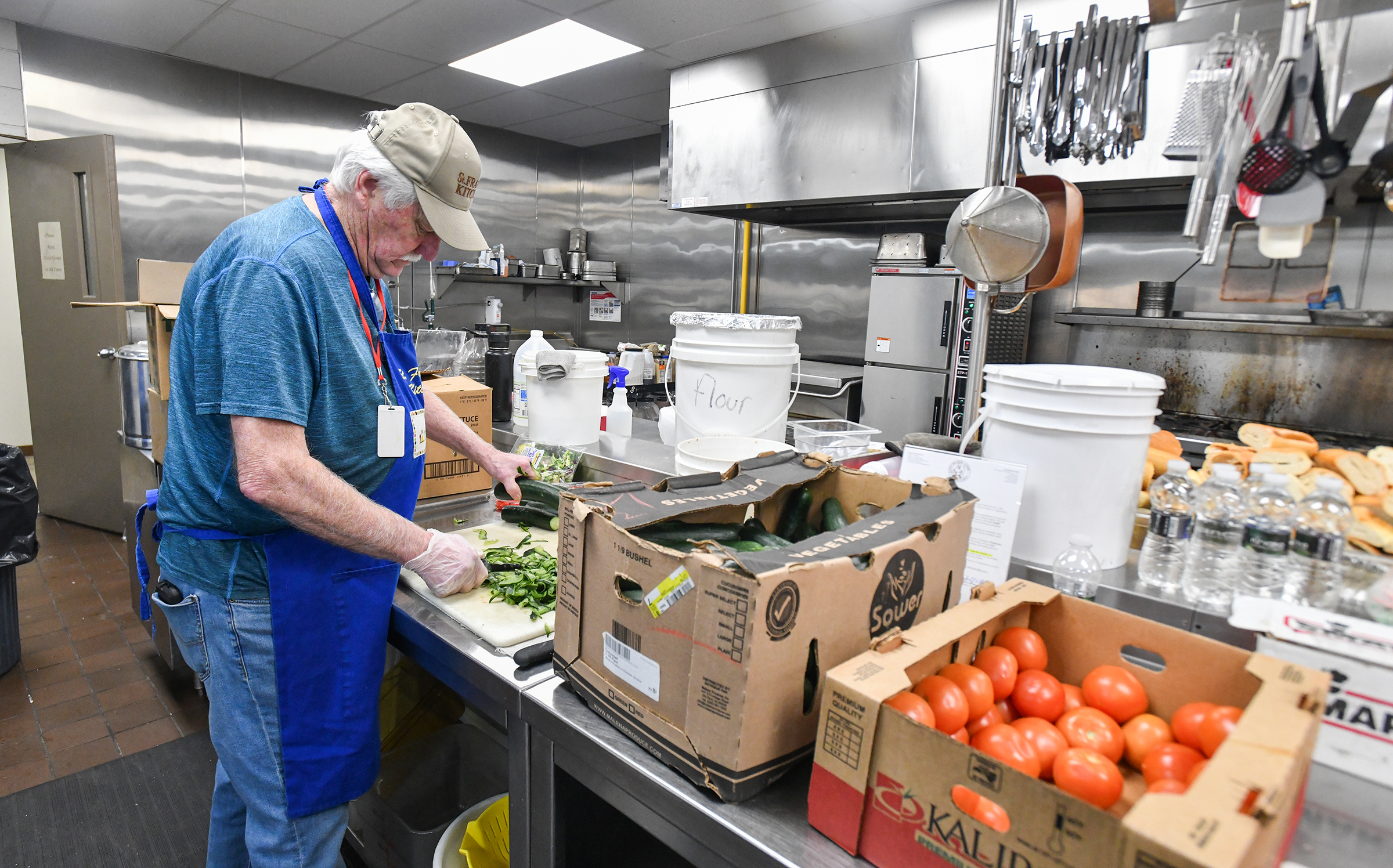 Volunteer Mike McDermott peels cucumbers in preparation for lunch at...