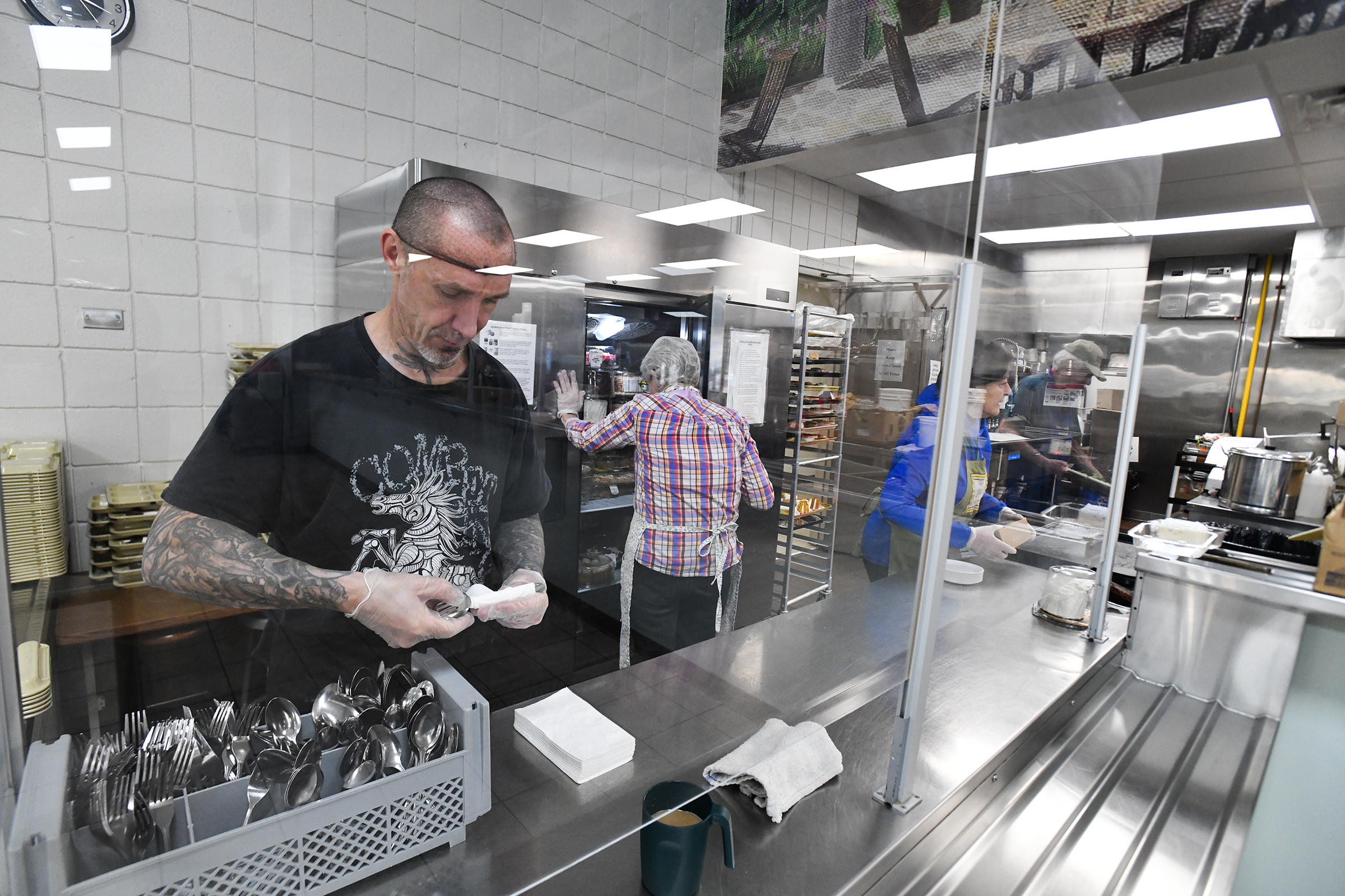 Volunteer Matthew Lerch rolls silverware in preparation for lunch at...